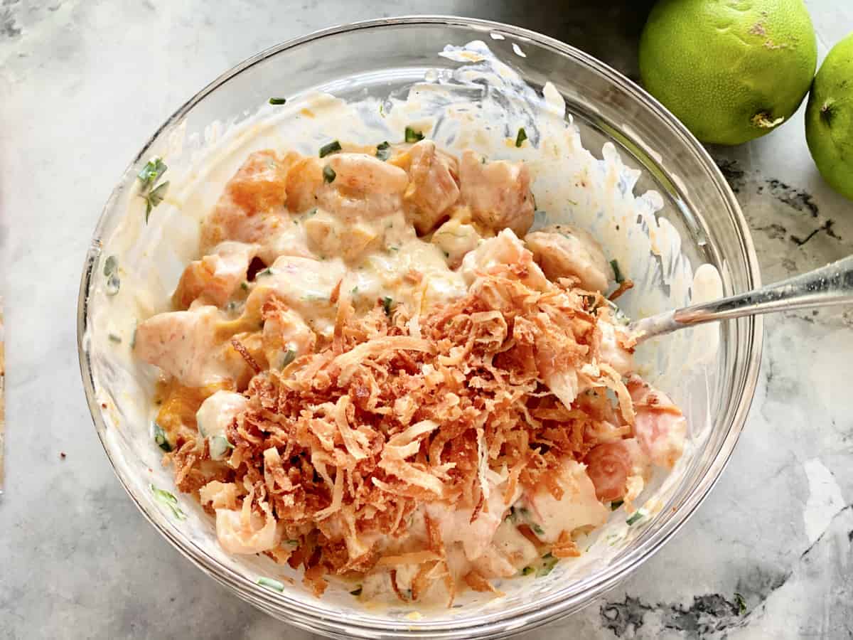 Top view of a glass bowl filled with shrimp salad and toasted coconut.