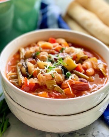 two white bowls stacked with minstrone soup.