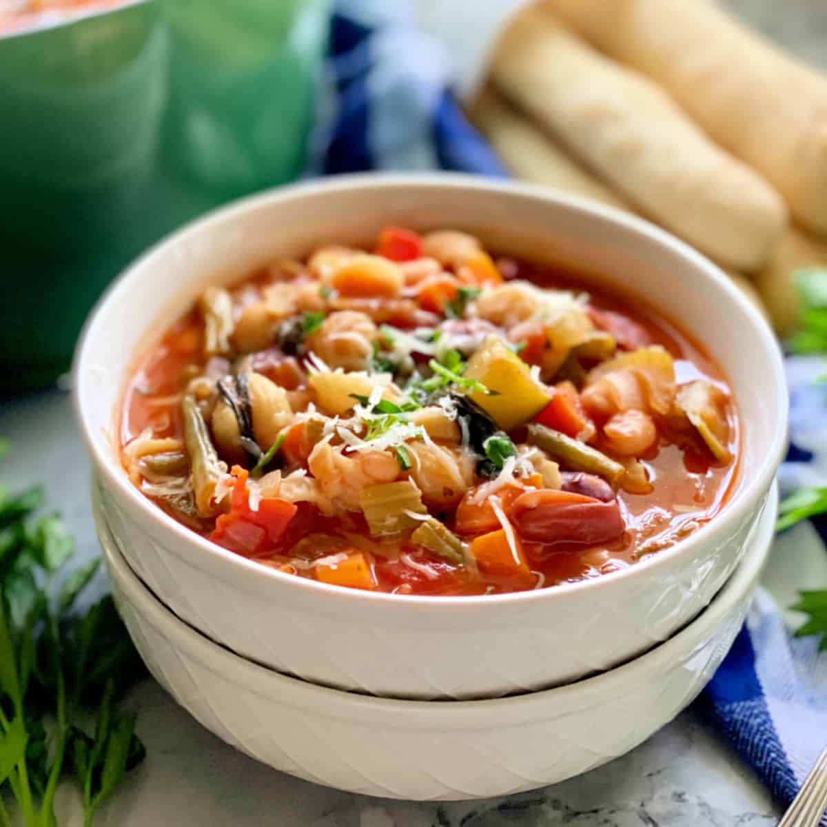 two white bowls stacked with minstrone soup.