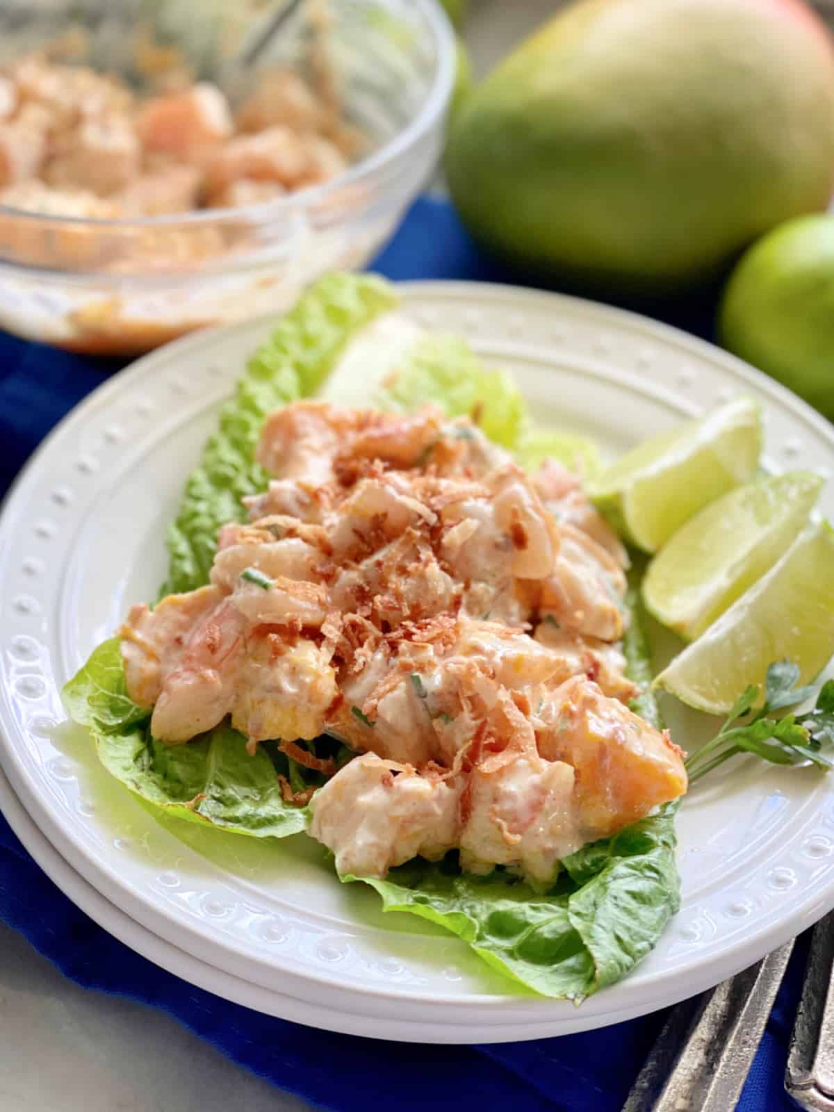 Close up of lettuce leaves with shrimp salad and lime wedges.