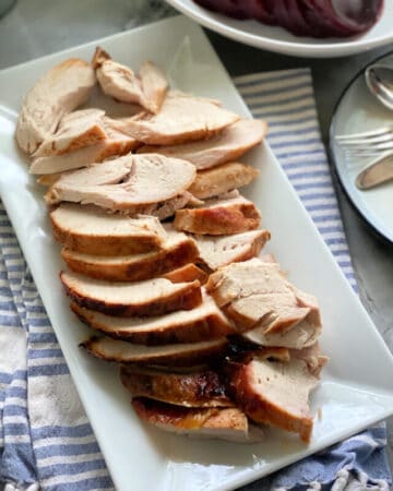 Top view of a plate filled with sliced turkey breast on a white platter.