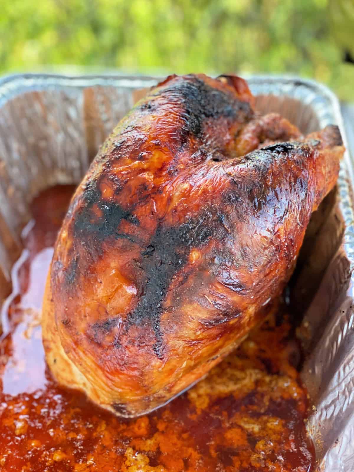 Golden brown turkey breast in a metal pan with juices.