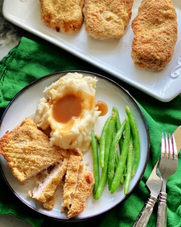 Sliced pork chops, mashed potatoes, and green beans on a plate.