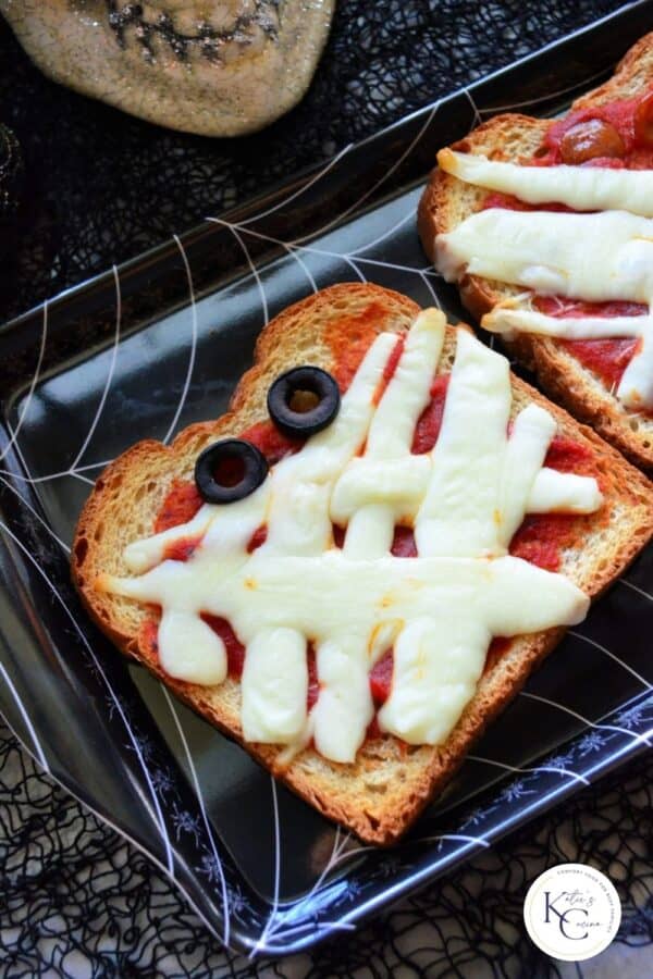 Top view of a slice of toast with tomato sauce, cheese and olives with logo on right corner.