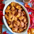 Top view of pumpkin bread pudding in an oval dish with fall leaves around it.