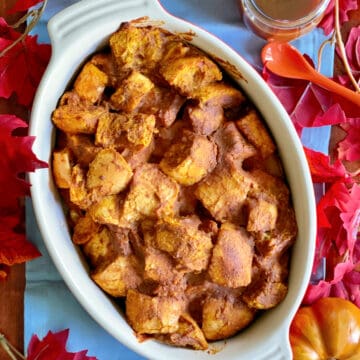 Top view of pumpkin bread pudding in an oval dish with fall leaves around it.