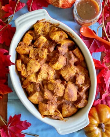 Top view of pumpkin bread pudding in an oval dish with fall leaves around it.