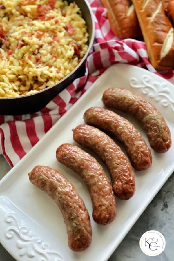 Top view of a white platter filled with brats and logo on the right corner.