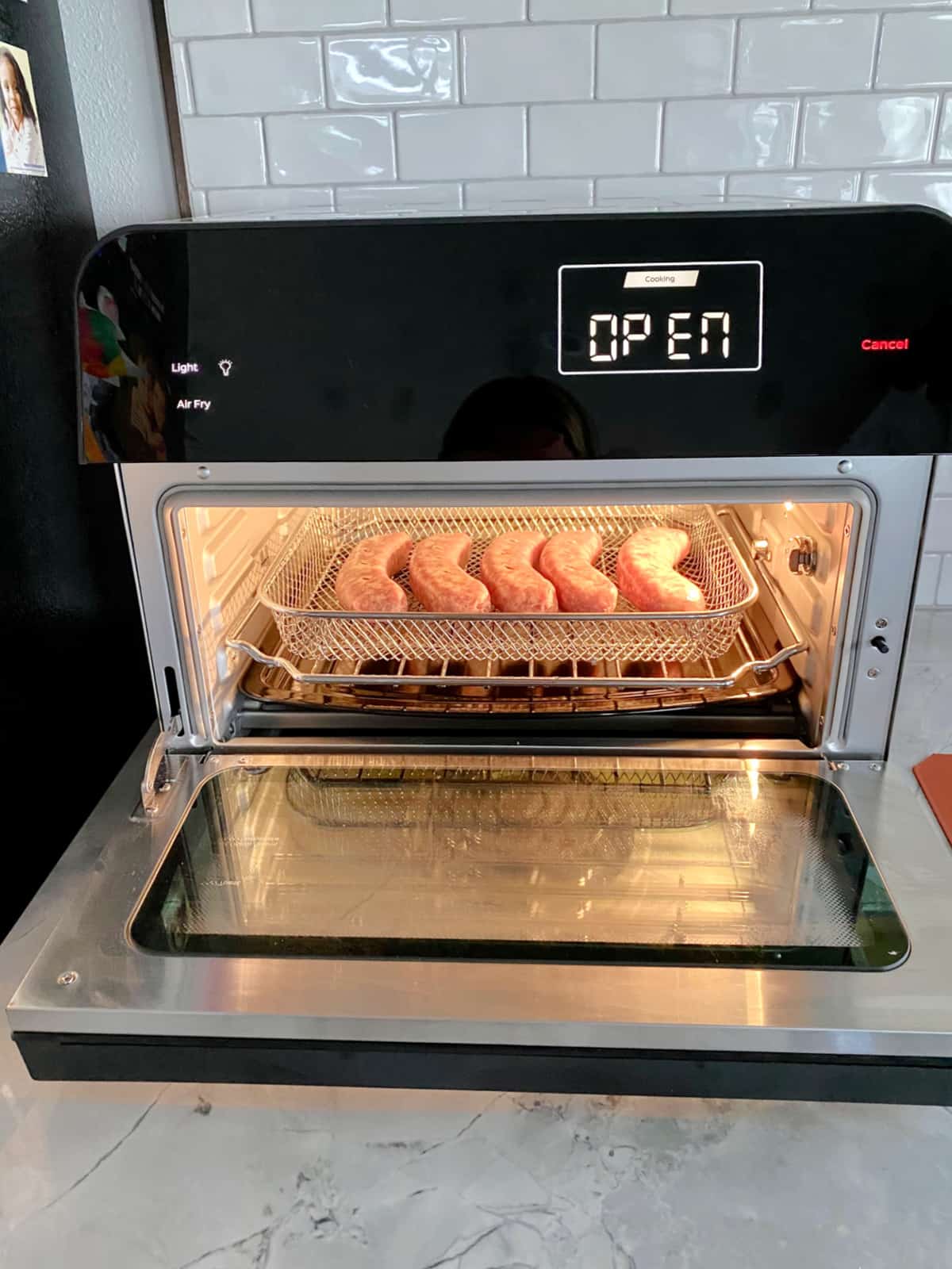 Instant brand toaster oven with brats in a wire basket .