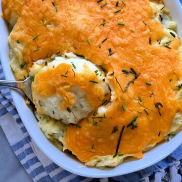 white oval baking dish filled with cheesey mashed potatoes.