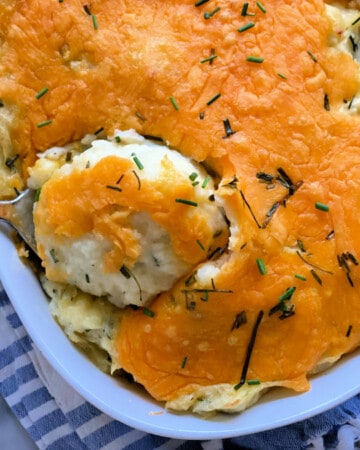 white oval baking dish filled with cheesey mashed potatoes.