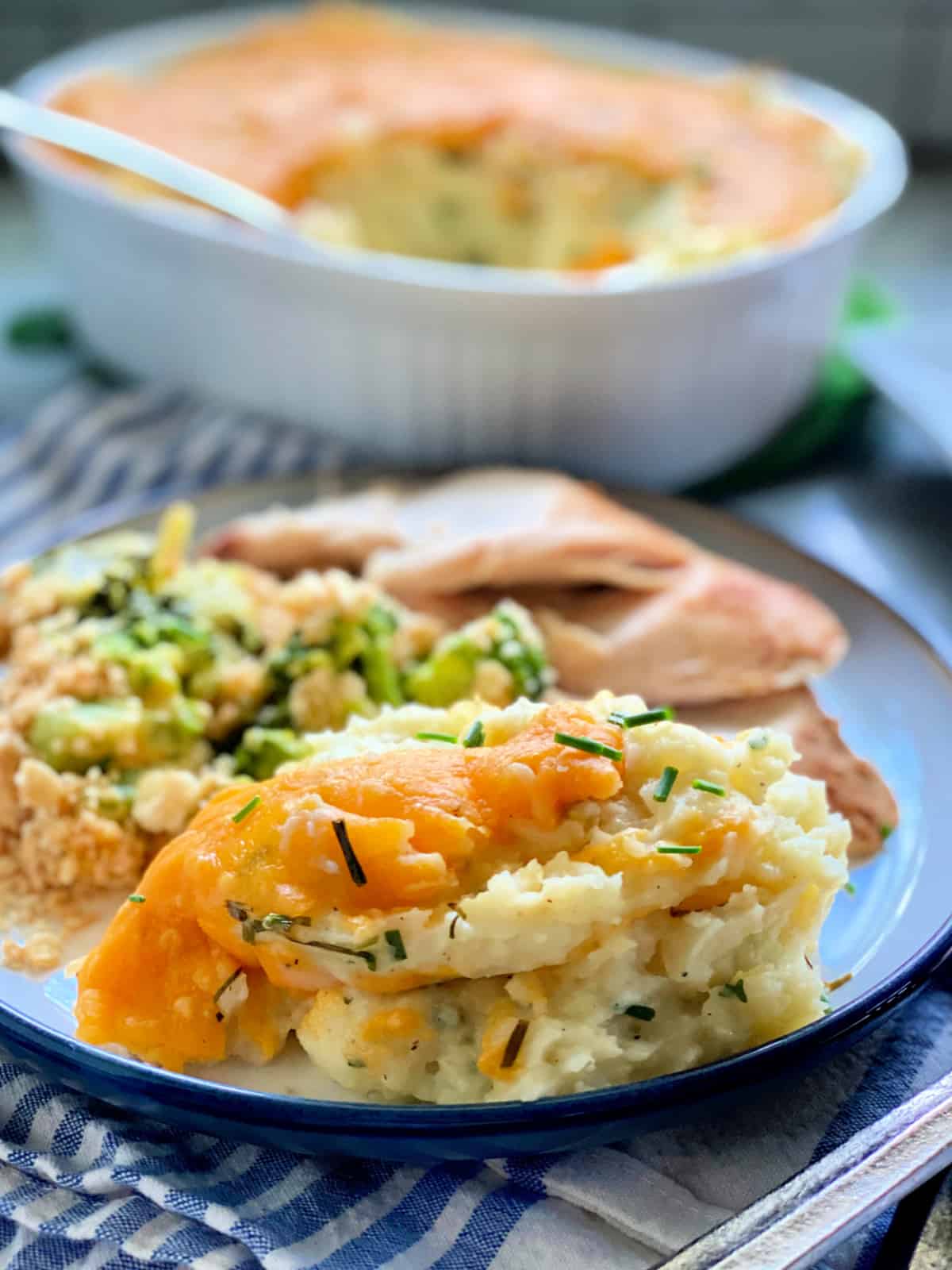 Plate full of Baked Cheddar and Chive Mashed Potatoes with turkey and broccoli casserole on it.