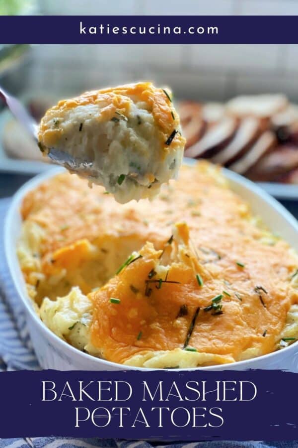 Spoon pulling a scoop of cheesy mashed potatoes from a white casserole dish with recipe title text on image for Pinterest.