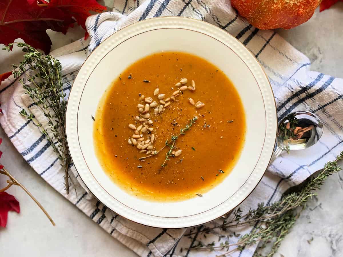 Top view of a white bowl with squash soup and pepitas.