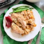White plate filled with turkey, stuffing, cranberry and green beans.