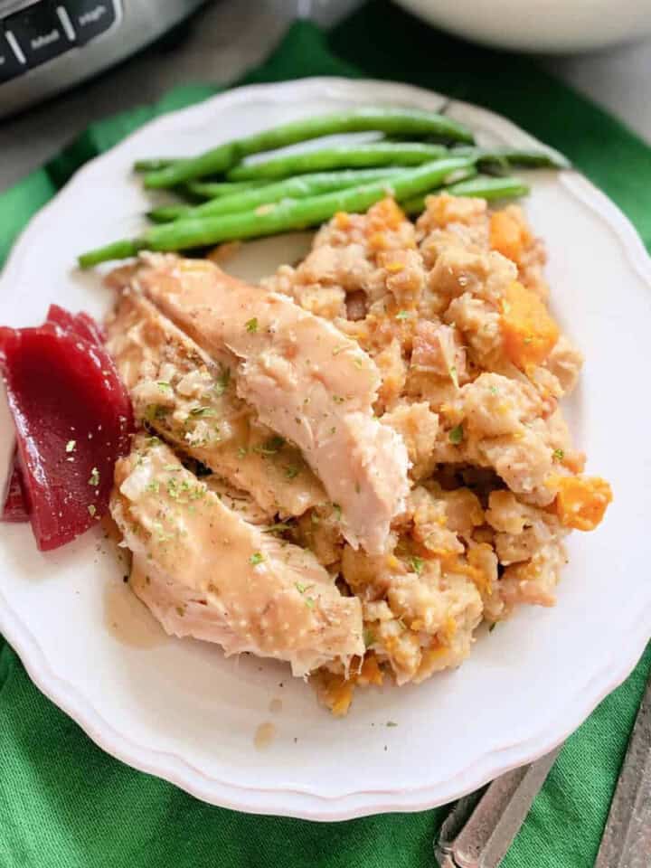 White plate filled with turkey, stuffing, cranberry and green beans.