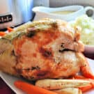 Whole turkey breast browned with parsnips and carrots on a white platter.