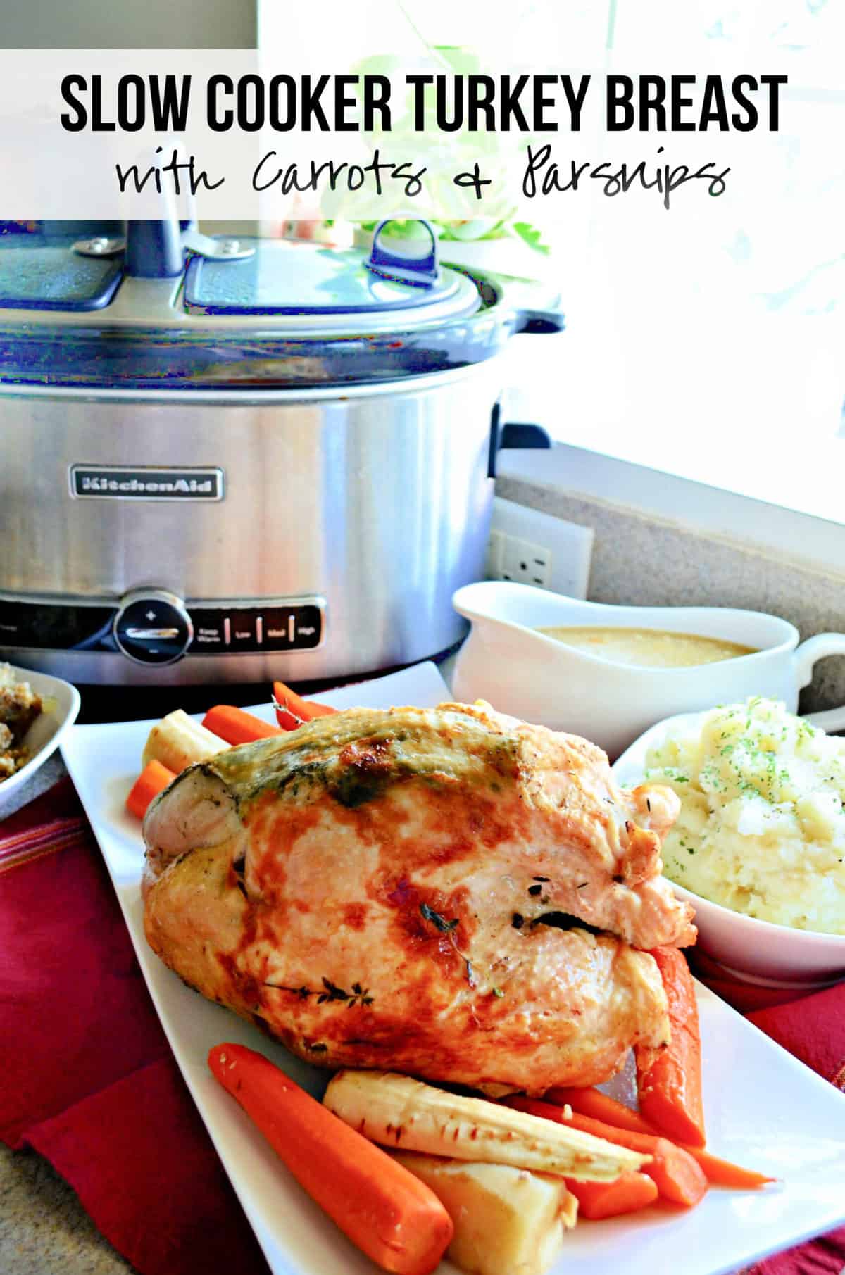 White platter filled with a cooked turkey breast, carrots, parsnips, and a slow cooker in the background.
