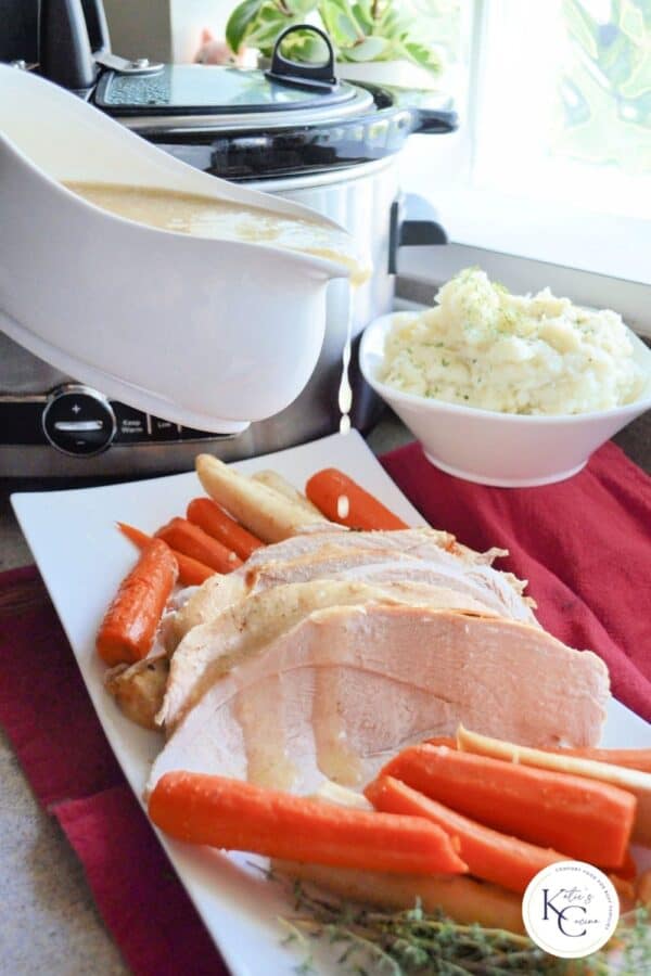 White gravy boat pouring gravy on top of sliced turkey with carrots and parsnips with logo on right corner..