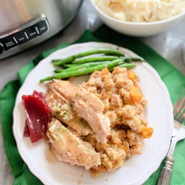 Top view of a turkey with stuffing and green beans on a green cloth.