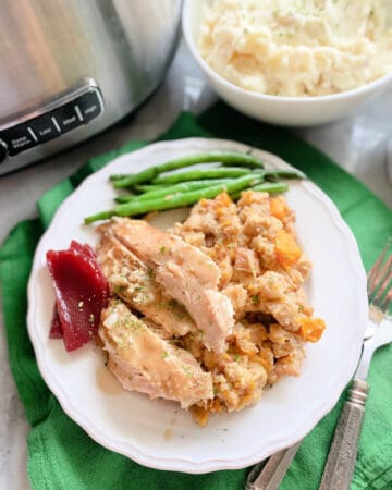 Top view of a turkey with stuffing and green beans on a green cloth.