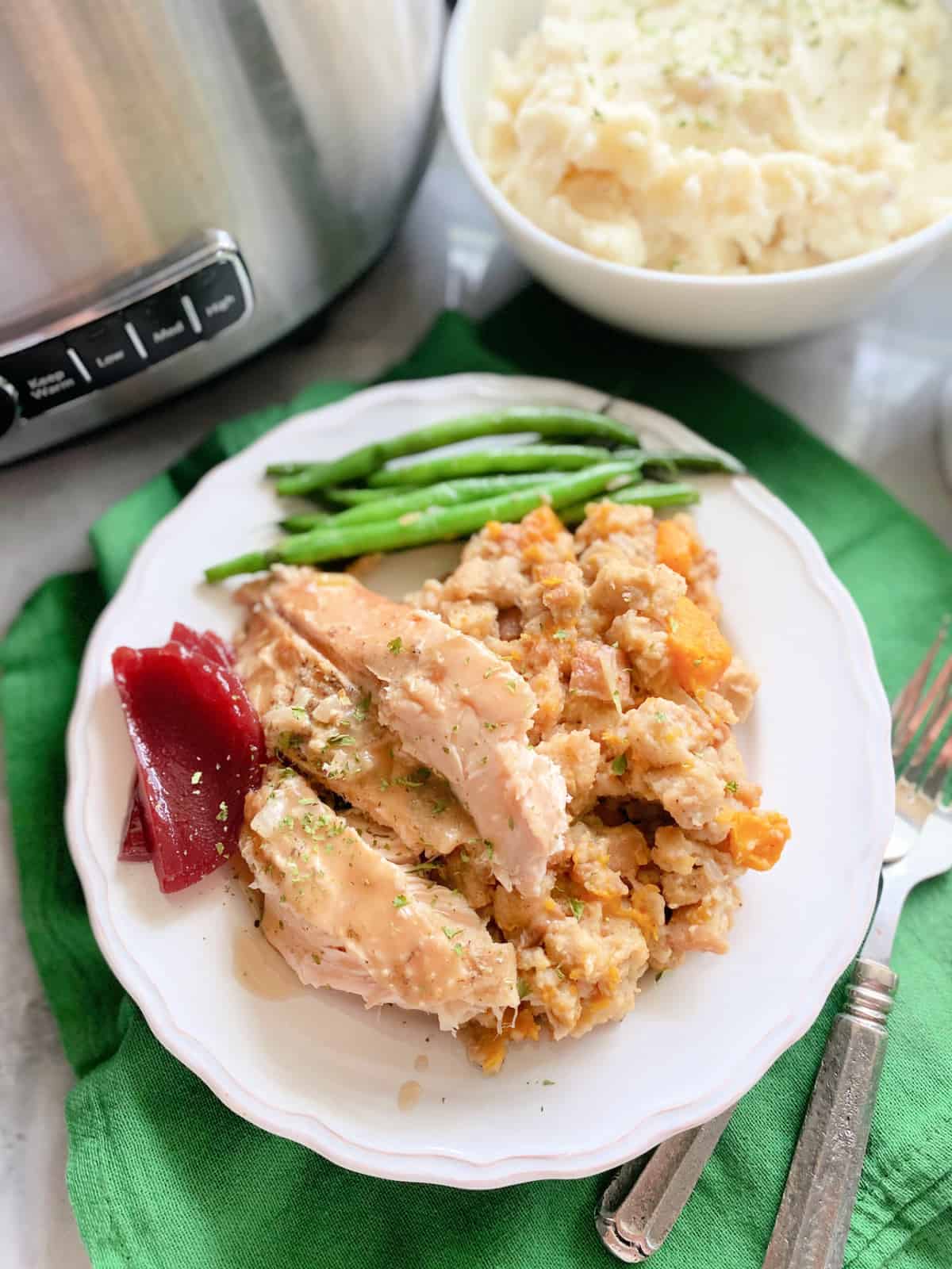 Top view of a turkey with stuffing and green beans on a green cloth.