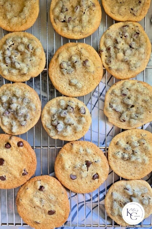 Top view of a wire rack full of chocolate chip cookies with logo on right corner.