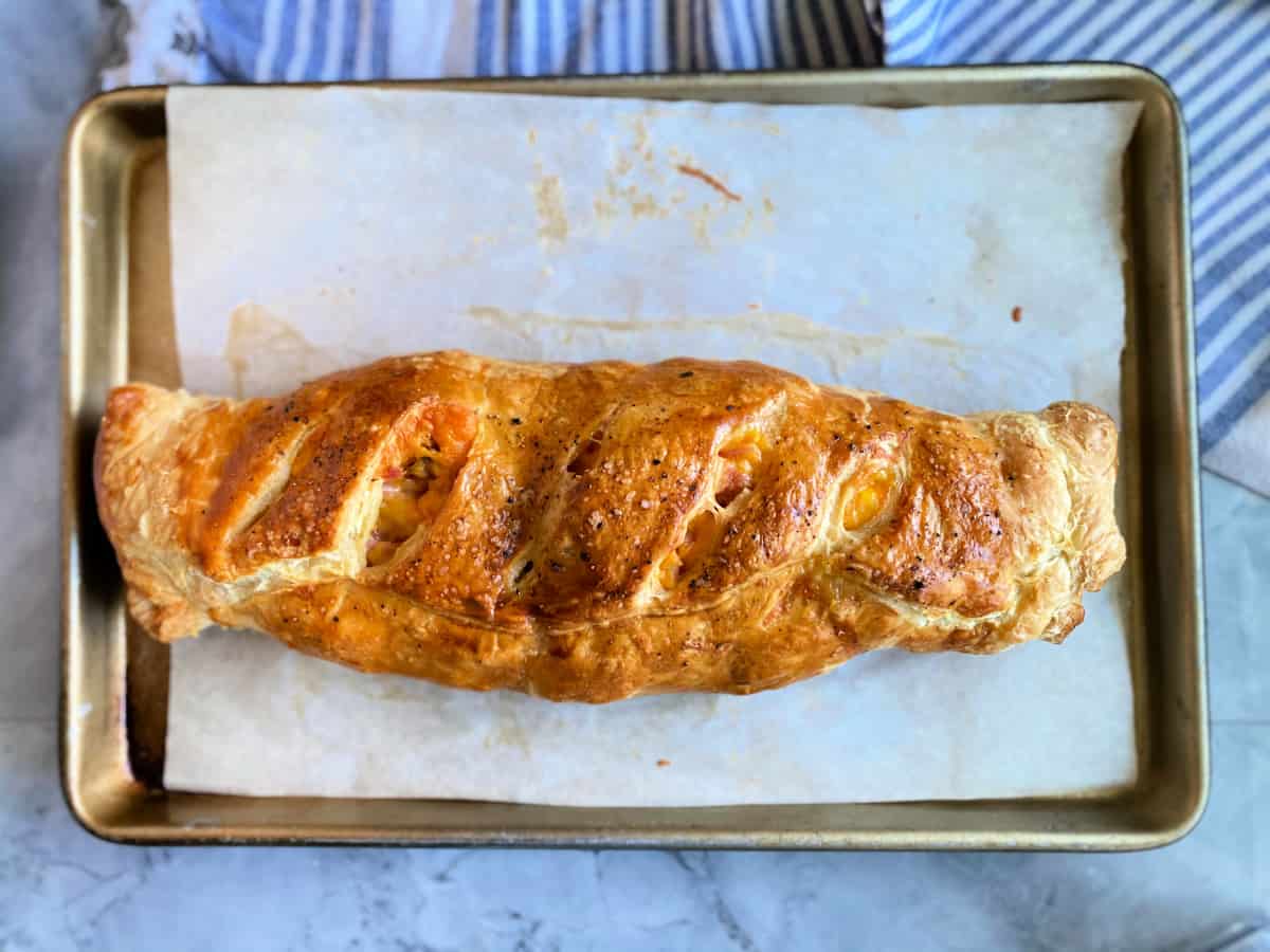 Top view of a baking sheet lined with parchment paper with a cooked puff pastry on top.