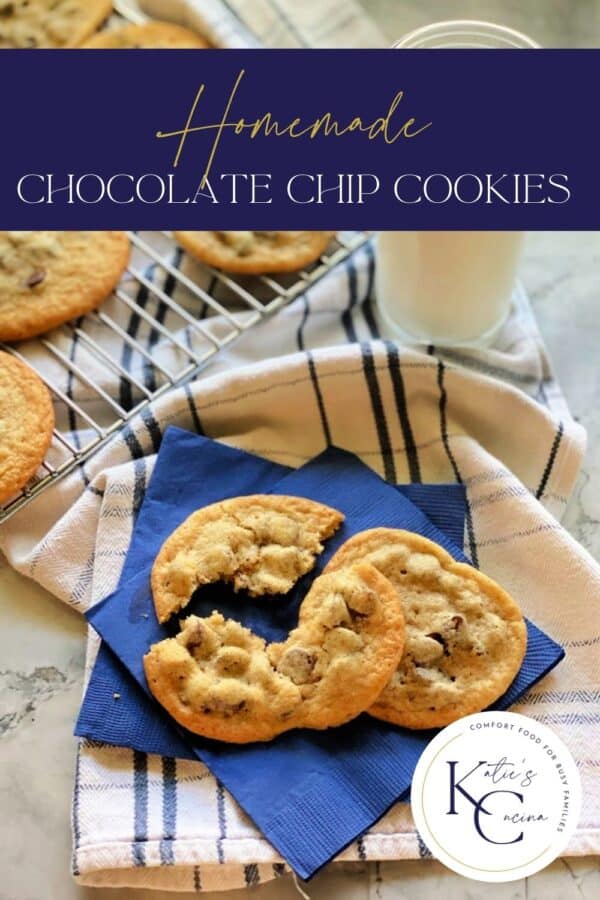 Two chocolate chip cookies broken on a blue napkin resting on a dish towel.