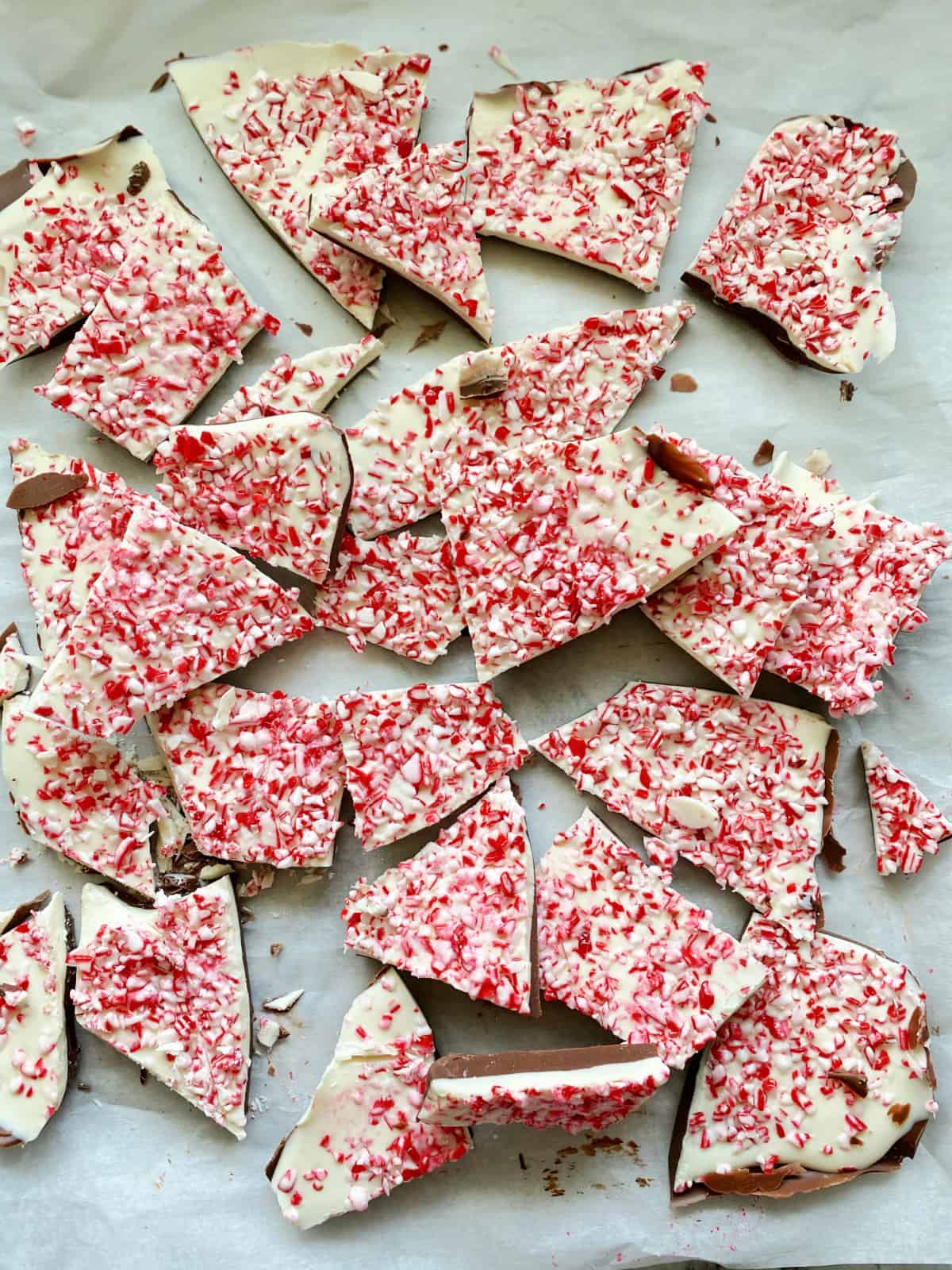 Top view of chopped Peppermint Bark in pieces on white parchment paper.