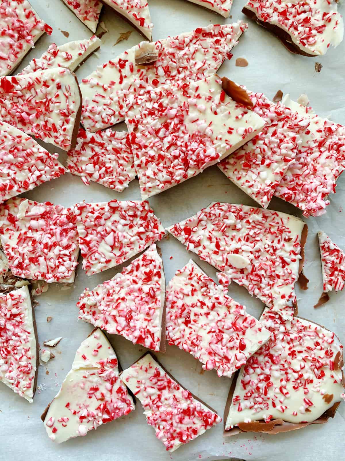 Close up of chopped Peppermint Bark on white paper.