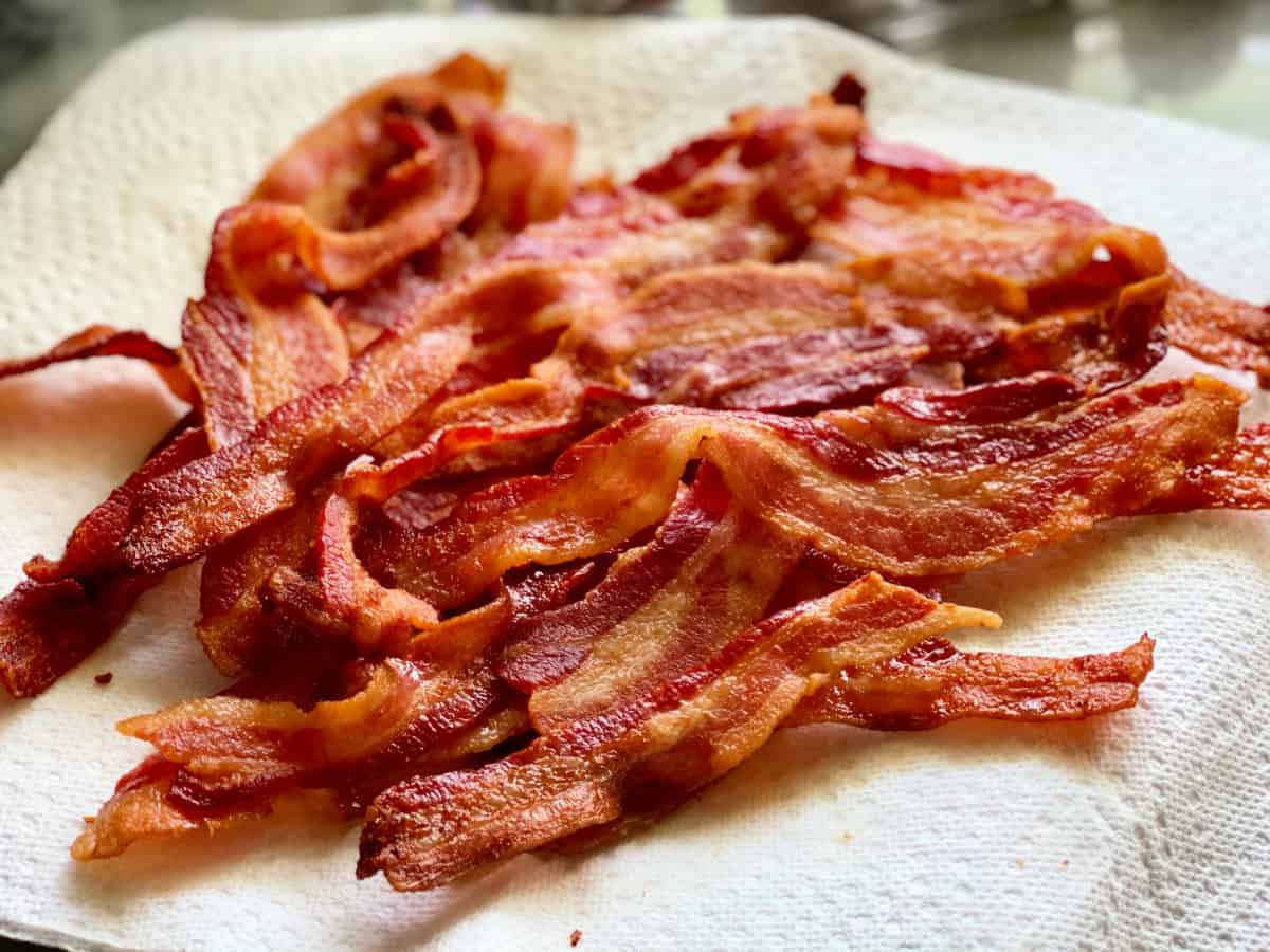 Multiple cooked slices of bacon resting on paper towel