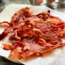 Square photo of a paper towel lined plate with crispy bacon