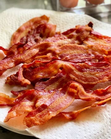 Square photo of a paper towel lined plate with crispy bacon