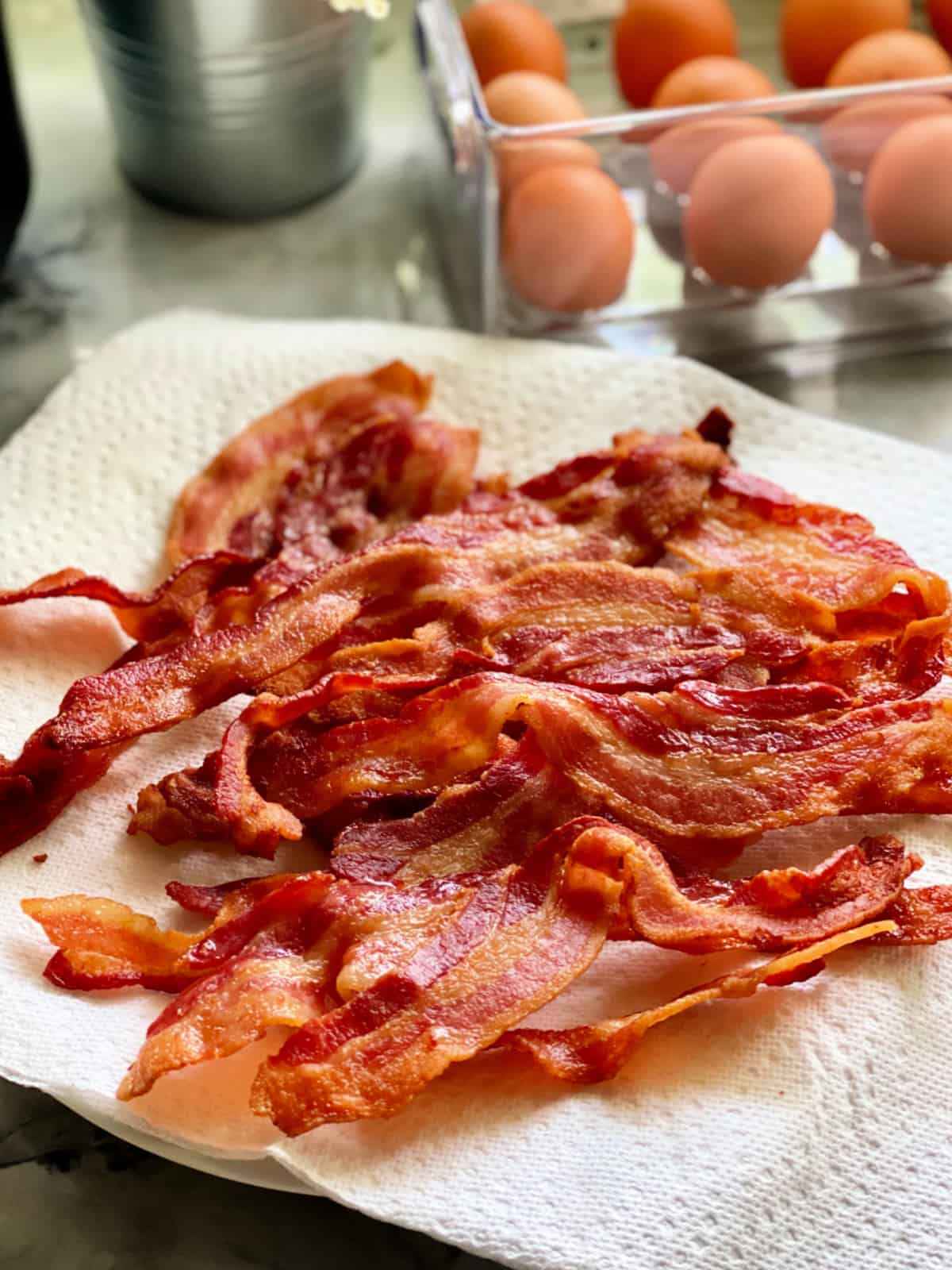 Multiple cooked slices of bacon resting on paper towel