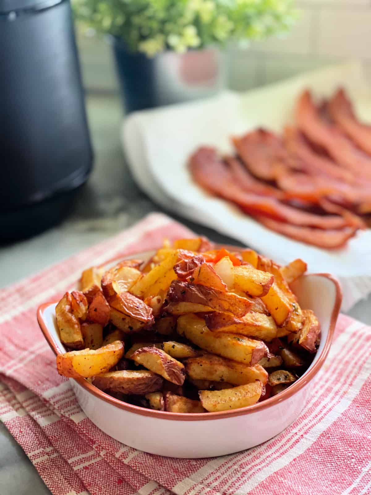 White dish with fried breakfast potatoes inside sitting on red and white towel