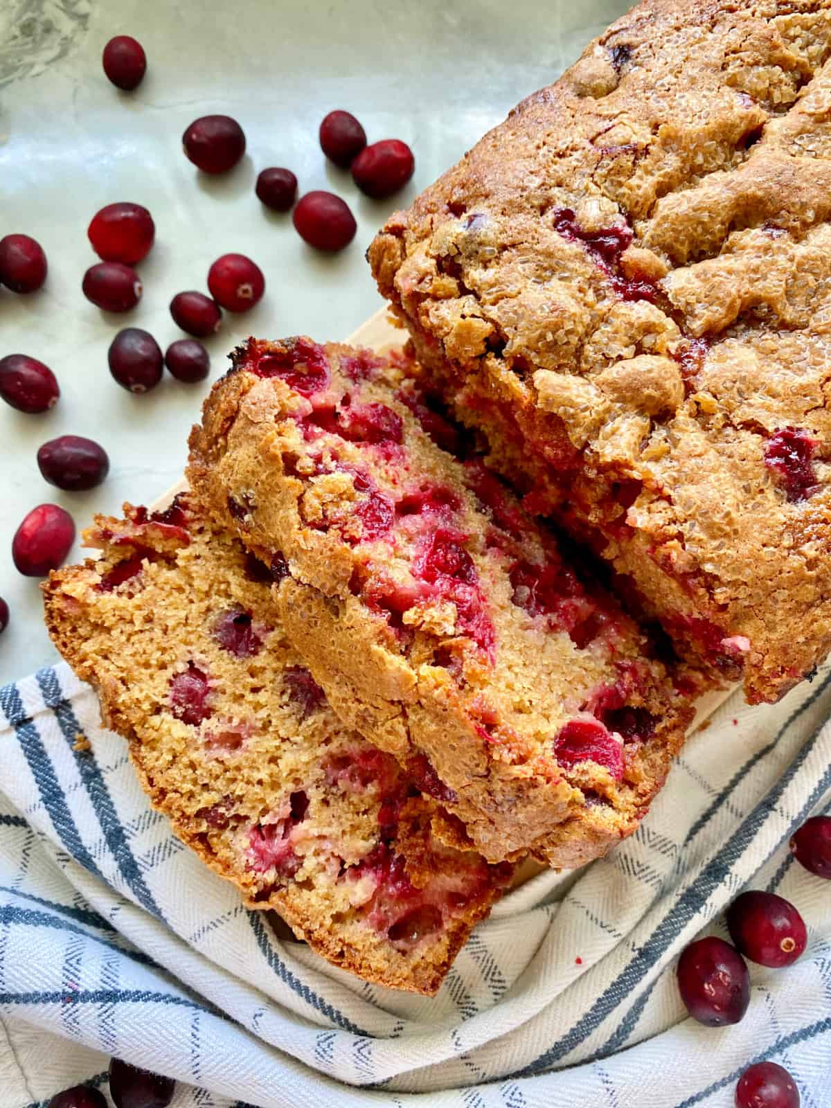 Two slices of Cranberry Bread cut from a loaf wrapped in a dish cloth.