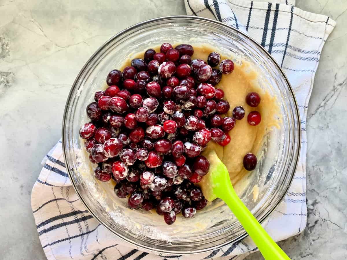 Glass bowl with batter and fresh cranberries on top.