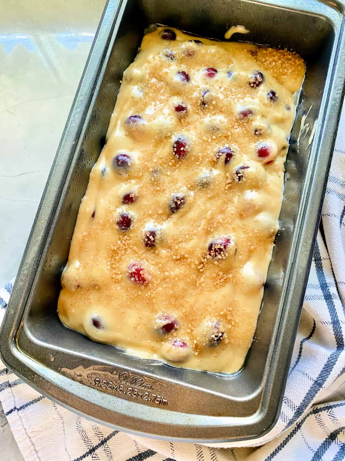 Top view of a metal loaf pan with batter and cranberries on top.