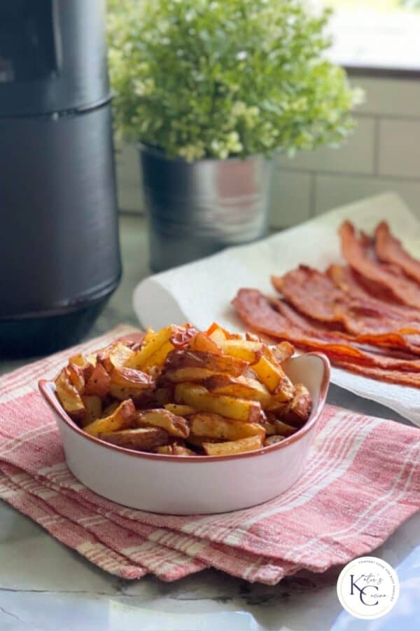 White dish with fried breakfast potatoes inside sitting on red and white towel