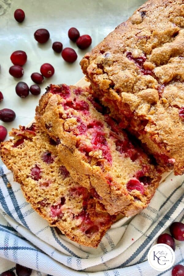 Three slices of Cranberry Bread with fresh cranberries around and logo on bottom right corner.