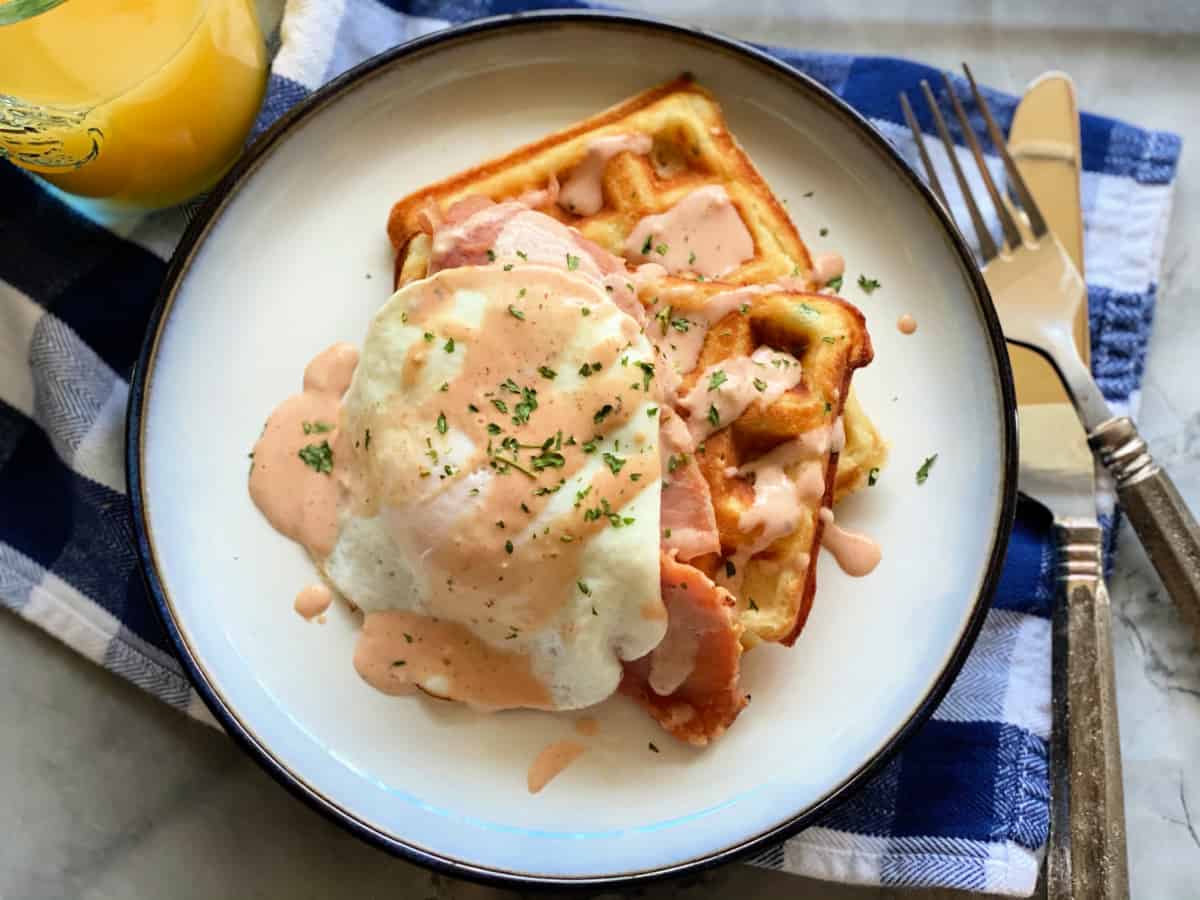 Top view shot of white plate with two waffles and an egg on top with sauce