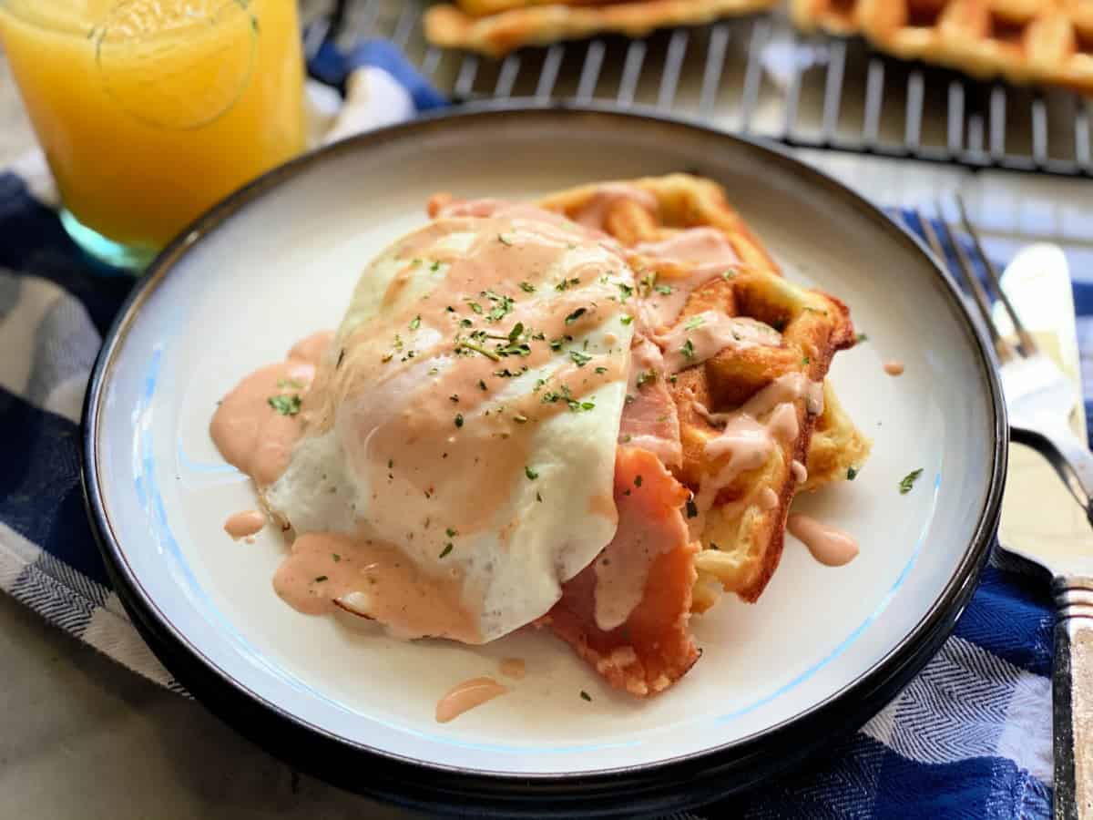 Top view shot of white plate with two waffles and an egg on top with sauce