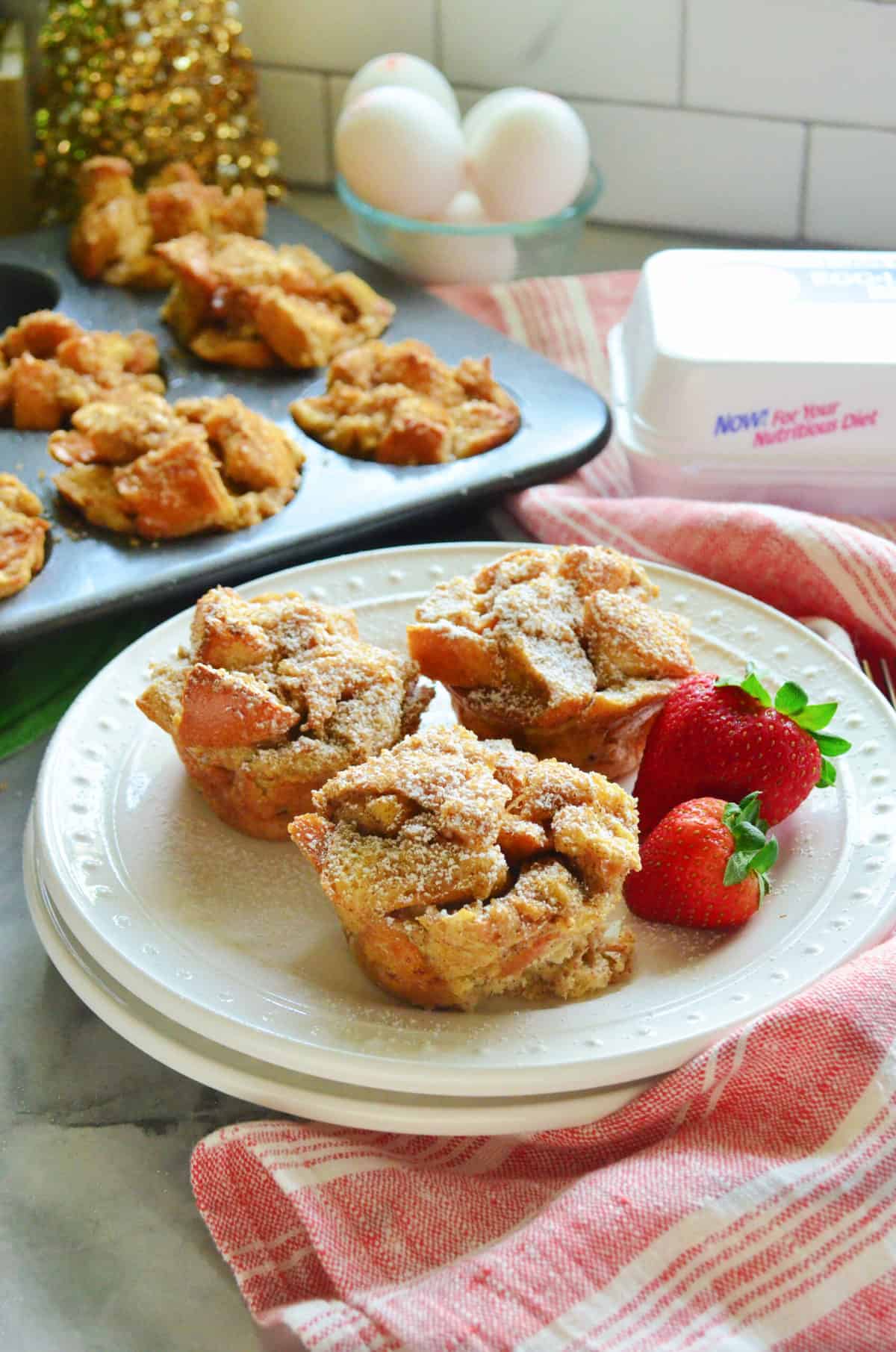 Three French toast muffins and strawberries on white plate