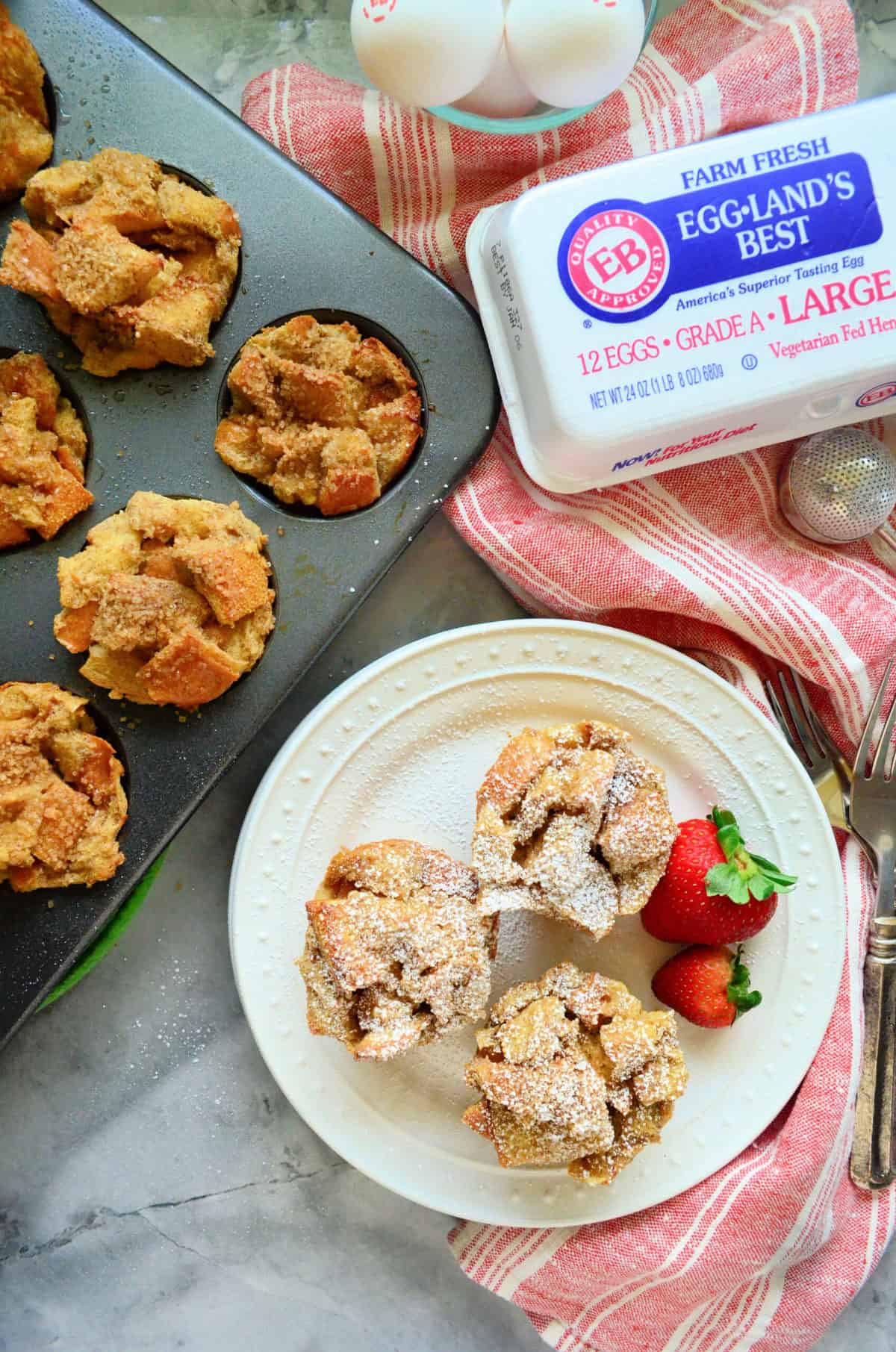 Top view of three French toast muffins on white plate with muffin pan on the side