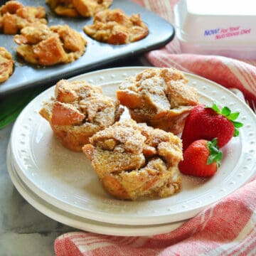 Square photo of a white plate with three french toast muffins and strawberries.