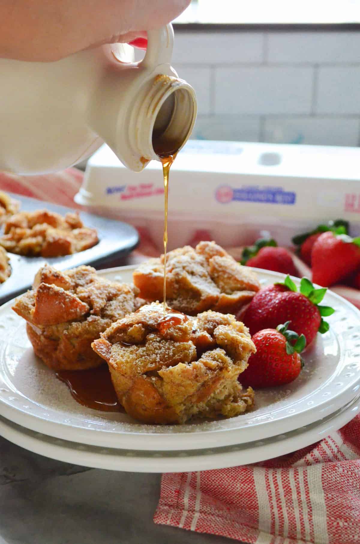 Three French toast muffins on white plate being drizzled with syrup