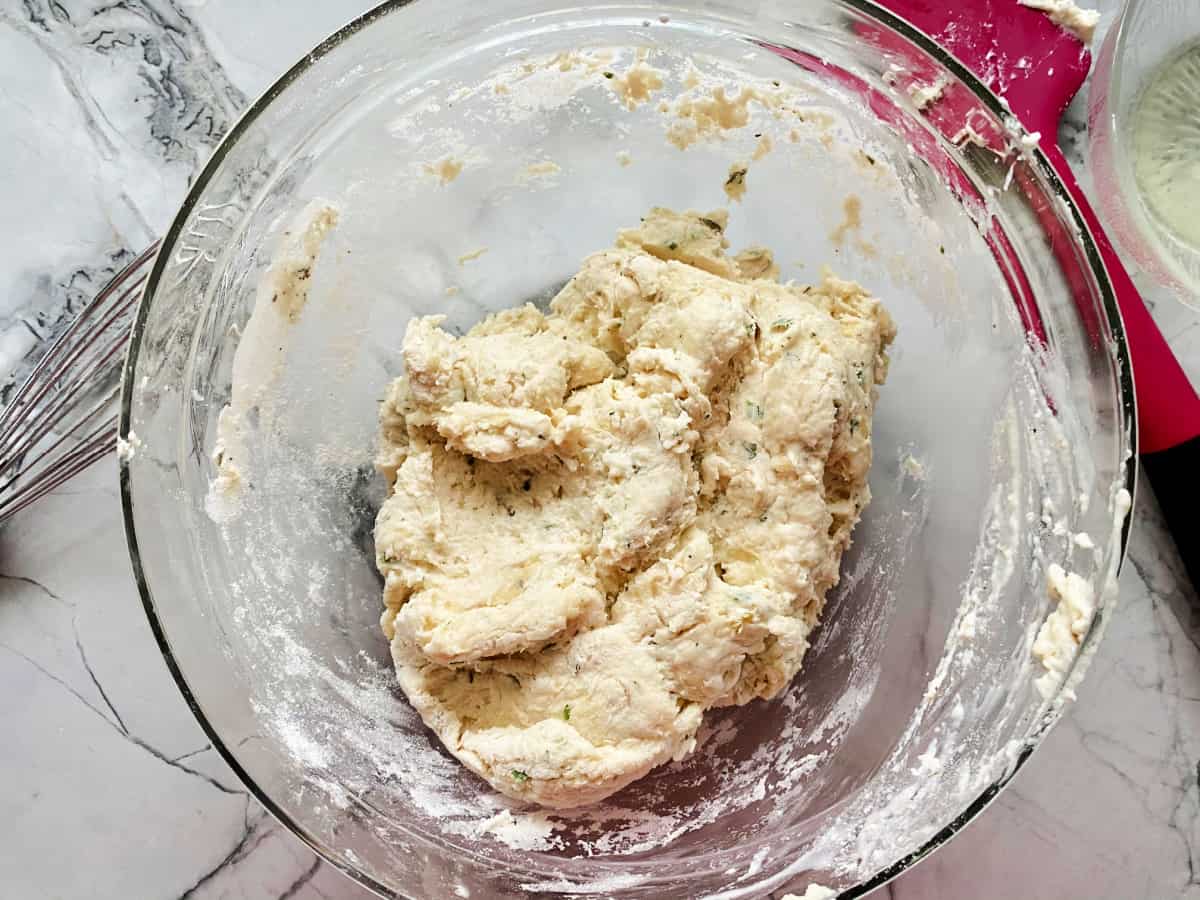 Dumpling mix in glass mixing bowl, red spatula on the side