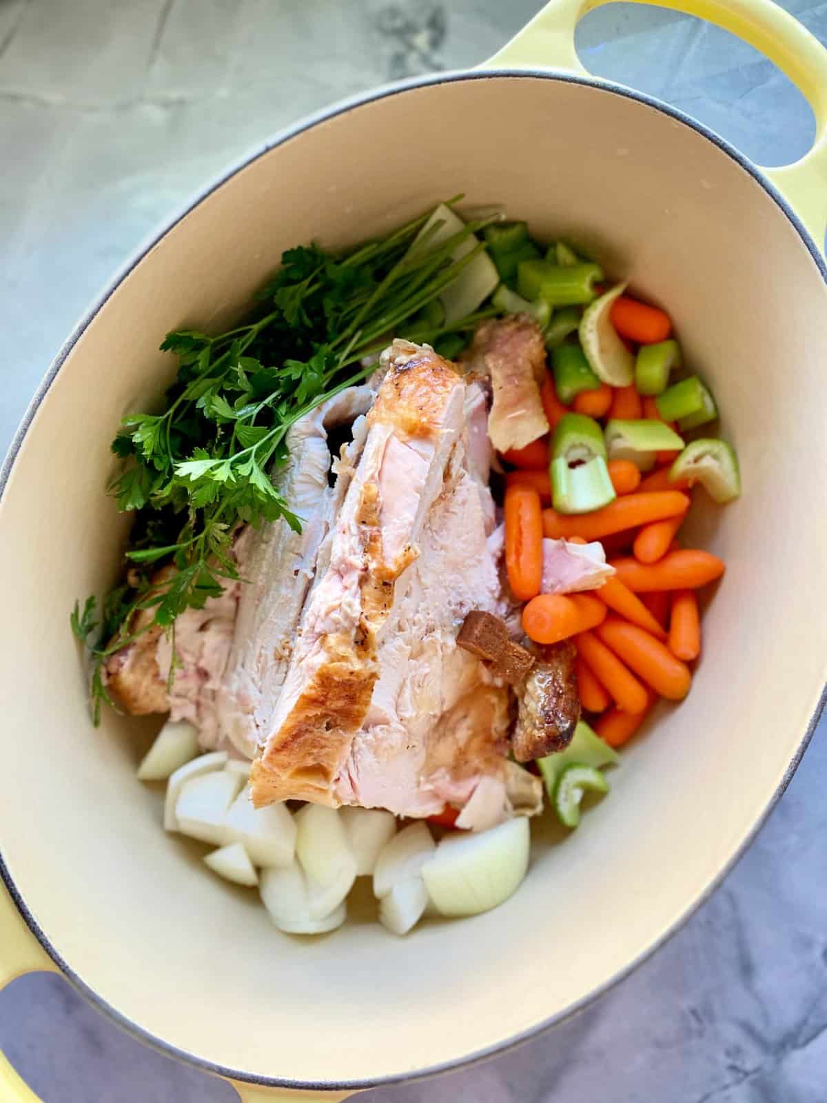 Top view of an oval pot filled with a chicken carcas and vegetables. 