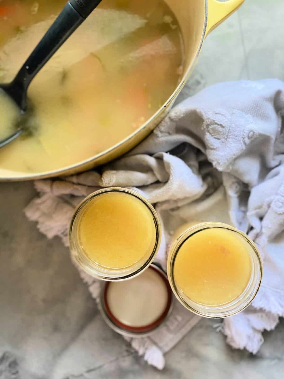Top view of an oval yellow baking dish with liquid in it and two mason jars filled with yellow liquid.